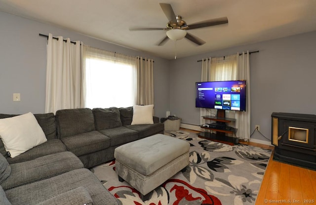 living area with baseboards, ceiling fan, wood finished floors, and baseboard heating