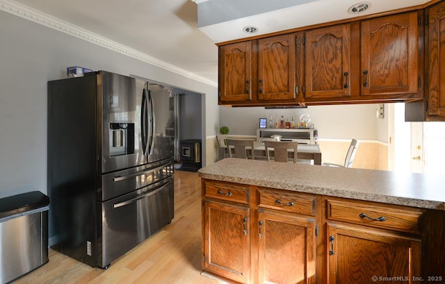 kitchen with crown molding, light wood-style floors, stainless steel refrigerator with ice dispenser, light countertops, and brown cabinets
