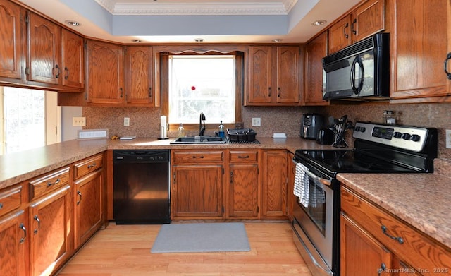 kitchen with brown cabinets, ornamental molding, a sink, and black appliances