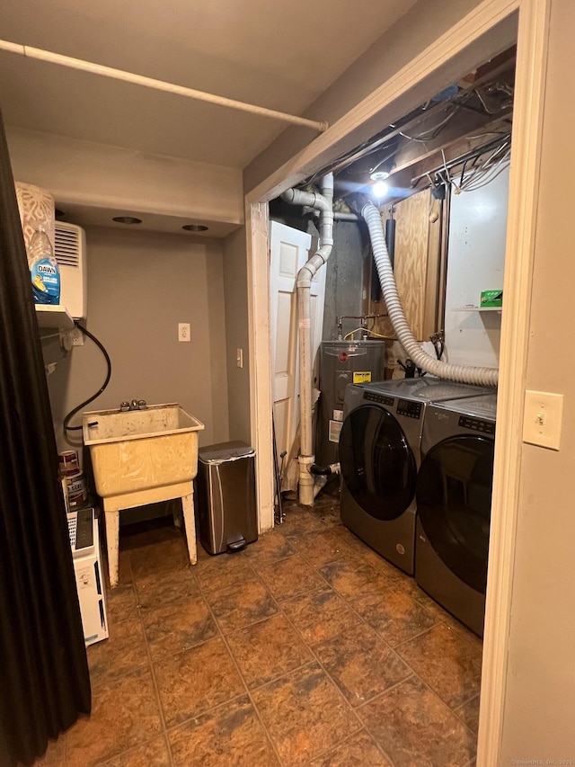 clothes washing area with independent washer and dryer, laundry area, a sink, stone finish floor, and water heater