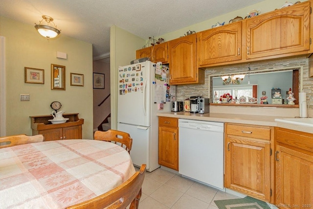 kitchen featuring light tile patterned flooring, a notable chandelier, white appliances, brown cabinetry, and light countertops