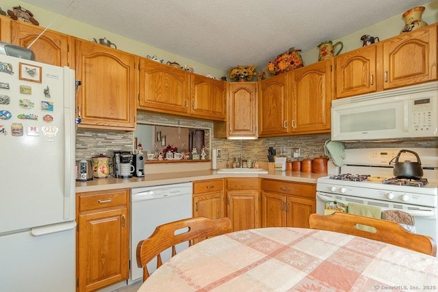 kitchen with white appliances, decorative backsplash, light countertops, a sink, and a textured ceiling