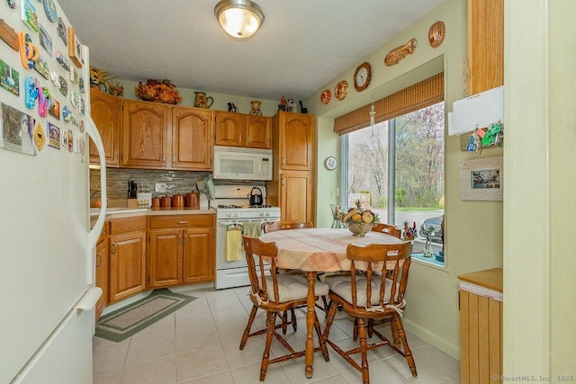 kitchen featuring tasteful backsplash, light countertops, light tile patterned flooring, white appliances, and brown cabinetry