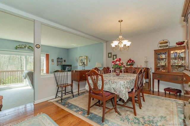 dining space featuring baseboards, wood finished floors, and a notable chandelier