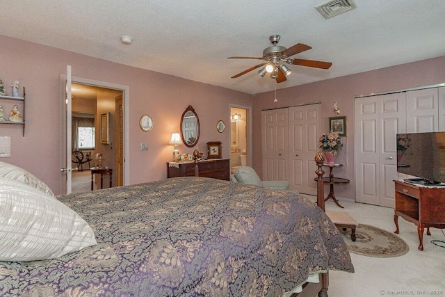 carpeted bedroom featuring visible vents, a ceiling fan, and multiple closets