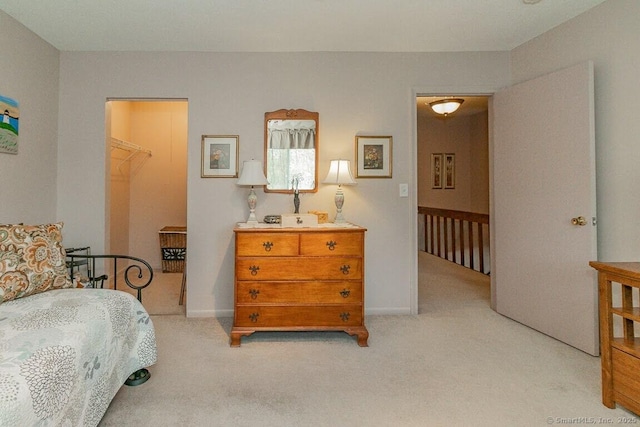 bedroom featuring baseboards, a spacious closet, and light carpet
