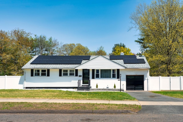ranch-style home featuring fence, an attached garage, entry steps, and solar panels