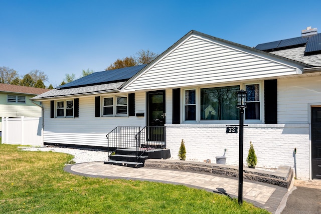 view of front of house featuring fence, solar panels, and a front lawn