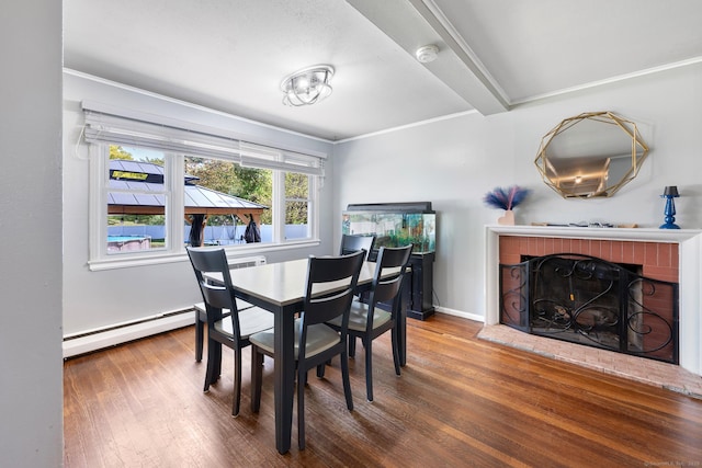dining room with ornamental molding, a baseboard heating unit, wood finished floors, and a brick fireplace