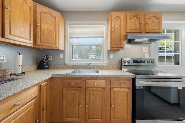 kitchen featuring a sink, light countertops, exhaust hood, and stainless steel range with electric stovetop