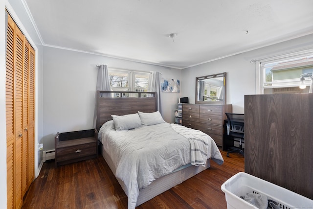 bedroom with wood-type flooring, crown molding, a baseboard heating unit, and a closet