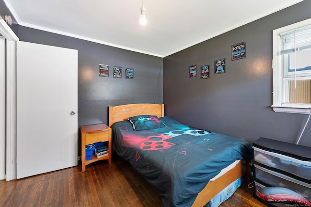 bedroom with ornamental molding and wood finished floors