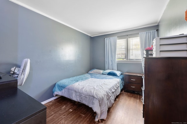 bedroom with crown molding, baseboards, and wood finished floors