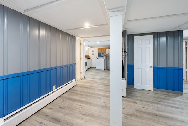 hall featuring baseboard heating, a decorative wall, and wood finished floors