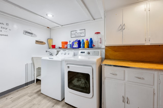laundry room featuring cabinet space, separate washer and dryer, and light wood-style floors