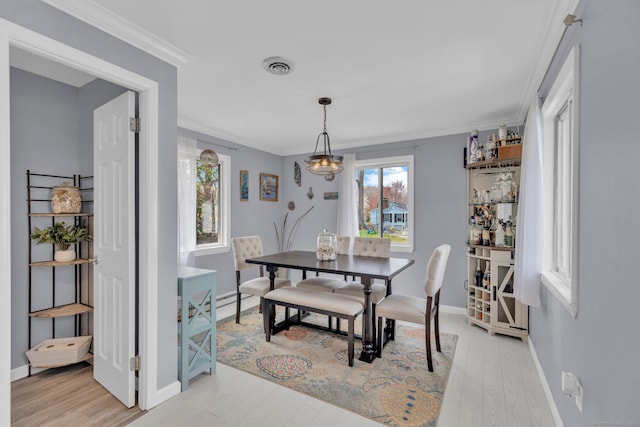 dining space with baseboards, visible vents, ornamental molding, and light wood-style flooring
