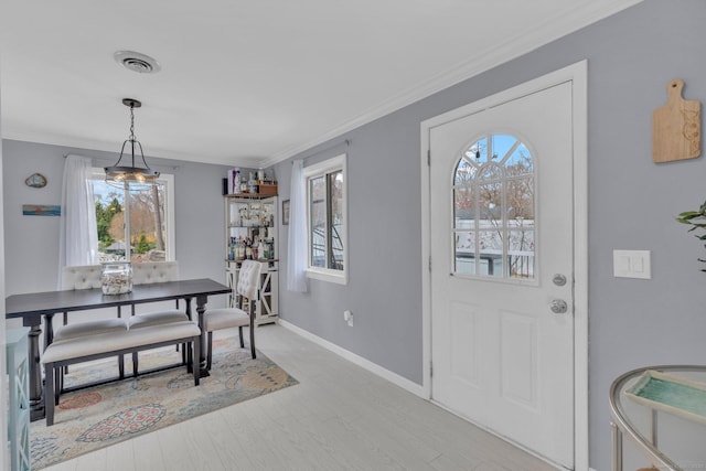 dining room featuring baseboards, visible vents, ornamental molding, and plenty of natural light