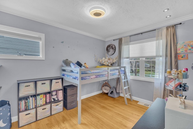 bedroom with visible vents, ornamental molding, a textured ceiling, and wood finished floors