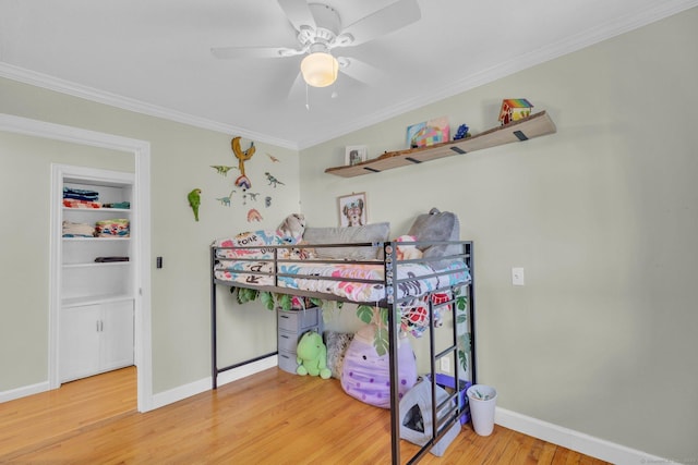 bedroom with baseboards, wood finished floors, a ceiling fan, and crown molding
