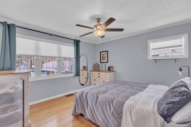 bedroom featuring crown molding, a ceiling fan, visible vents, baseboards, and wood finished floors