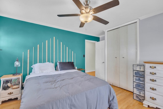 bedroom featuring wood finished floors, ceiling fan, a closet, and crown molding