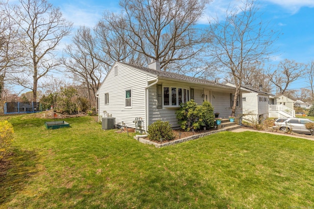 view of home's exterior featuring a chimney, a trampoline, central AC, and a yard