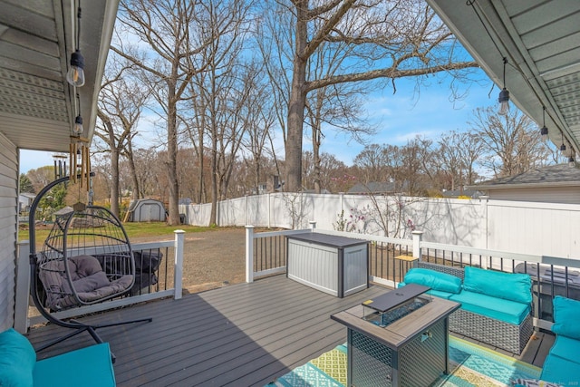 wooden deck with an outdoor living space with a fire pit, a storage unit, an outbuilding, and a fenced backyard