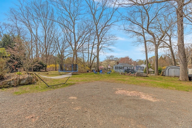 view of yard featuring a trampoline, an outdoor structure, and a storage shed