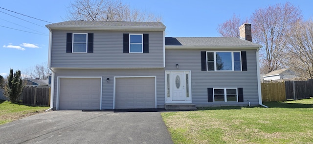view of front of house featuring driveway, a chimney, an attached garage, and fence