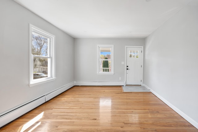 entrance foyer with baseboards, light wood-type flooring, and a baseboard heating unit