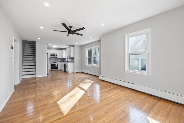 unfurnished living room with recessed lighting, light wood-style floors, stairs, a ceiling fan, and baseboard heating