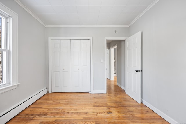unfurnished bedroom with a baseboard heating unit, crown molding, multiple windows, and light wood-style floors