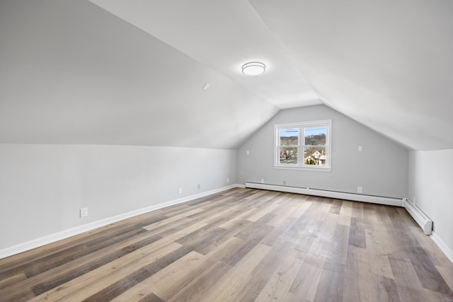 bonus room with baseboards, vaulted ceiling, wood finished floors, and a baseboard radiator