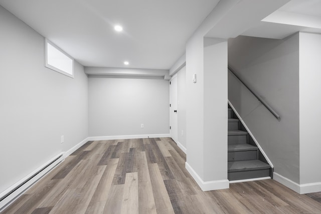 basement featuring a baseboard heating unit, baseboards, recessed lighting, wood finished floors, and stairs