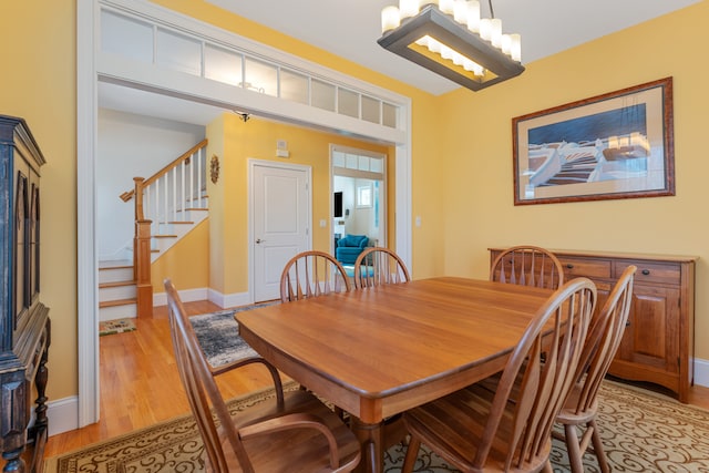 6 Holdridge Ct, Groton, CT 06355 - dining area with baseboards, light wood-type flooring, a notable chandelier, and stairway