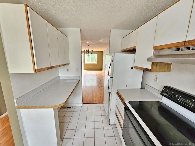 kitchen featuring a textured ceiling, light countertops, under cabinet range hood, electric range, and a notable chandelier