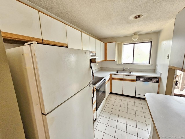 kitchen with a sink, under cabinet range hood, light tile patterned floors, white appliances, and light countertops
