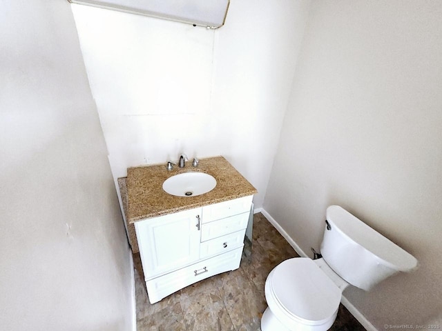bathroom featuring toilet, vanity, and baseboards