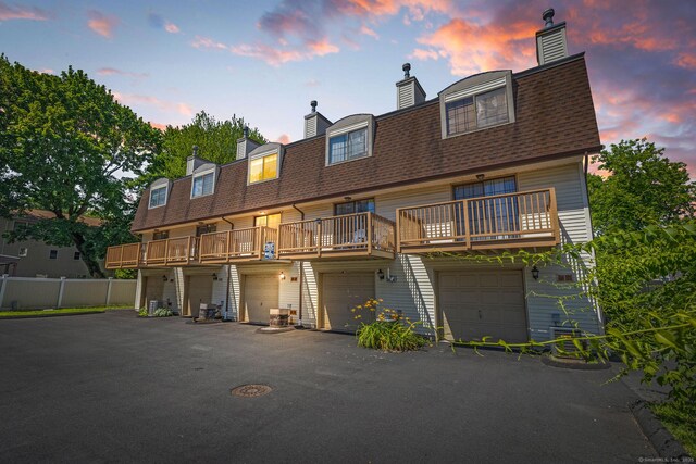 268 Lawlor St Apt 6, New Britain, CT 06051 - back of house at dusk with a chimney, an attached garage, and a shingled roof
