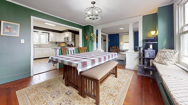 dining space with crown molding, hardwood / wood-style floors, decorative columns, and baseboards