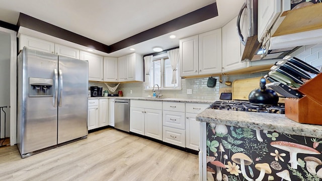 kitchen featuring light wood-style flooring, a sink, appliances with stainless steel finishes, and white cabinetry