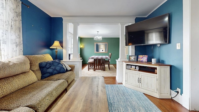 living room featuring baseboards, ornate columns, wood finished floors, and crown molding