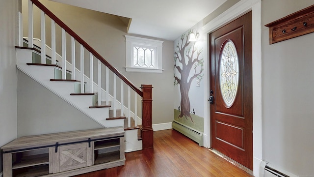 foyer entrance with baseboards, wood finished floors, stairs, and a baseboard radiator