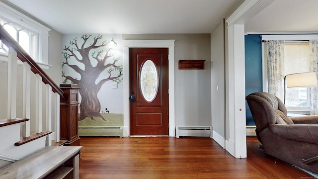foyer entrance with a baseboard radiator, wood finished floors, baseboard heating, and stairs