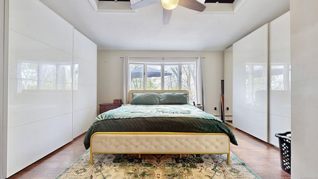 bedroom featuring ceiling fan, wood finished floors, and a baseboard radiator