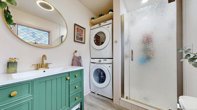 bathroom with stacked washer / drying machine, a stall shower, toilet, wood finished floors, and vanity