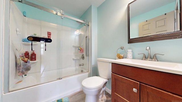 bathroom with wood finished floors, bath / shower combo with glass door, toilet, and vanity