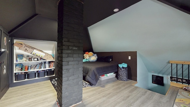 bedroom with ornate columns, wood finished floors, and vaulted ceiling