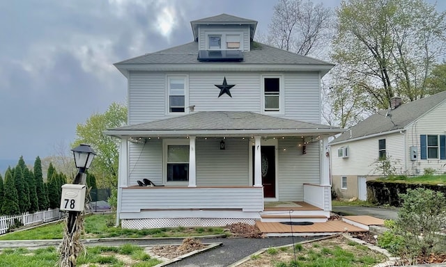 american foursquare style home with fence, covered porch, and a shingled roof