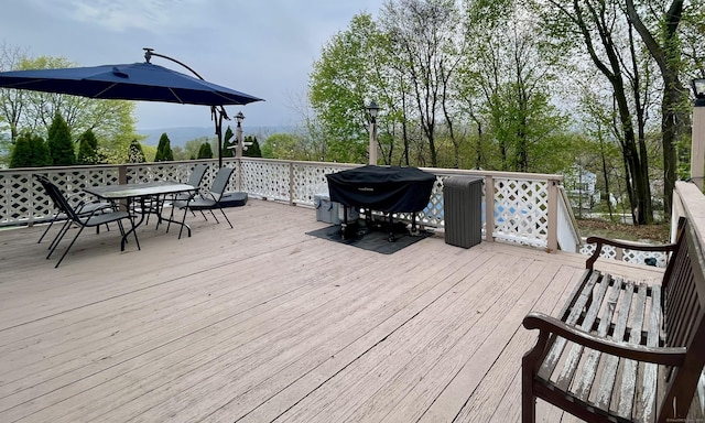 wooden terrace with outdoor dining area and area for grilling